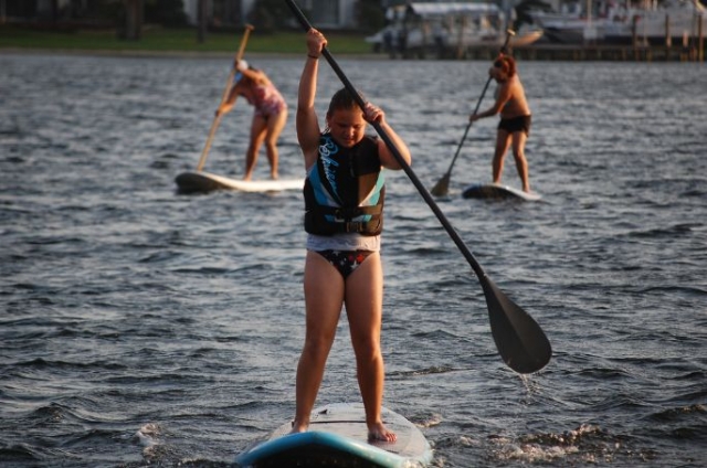 nina y dos mujeres en el agua practicando sup